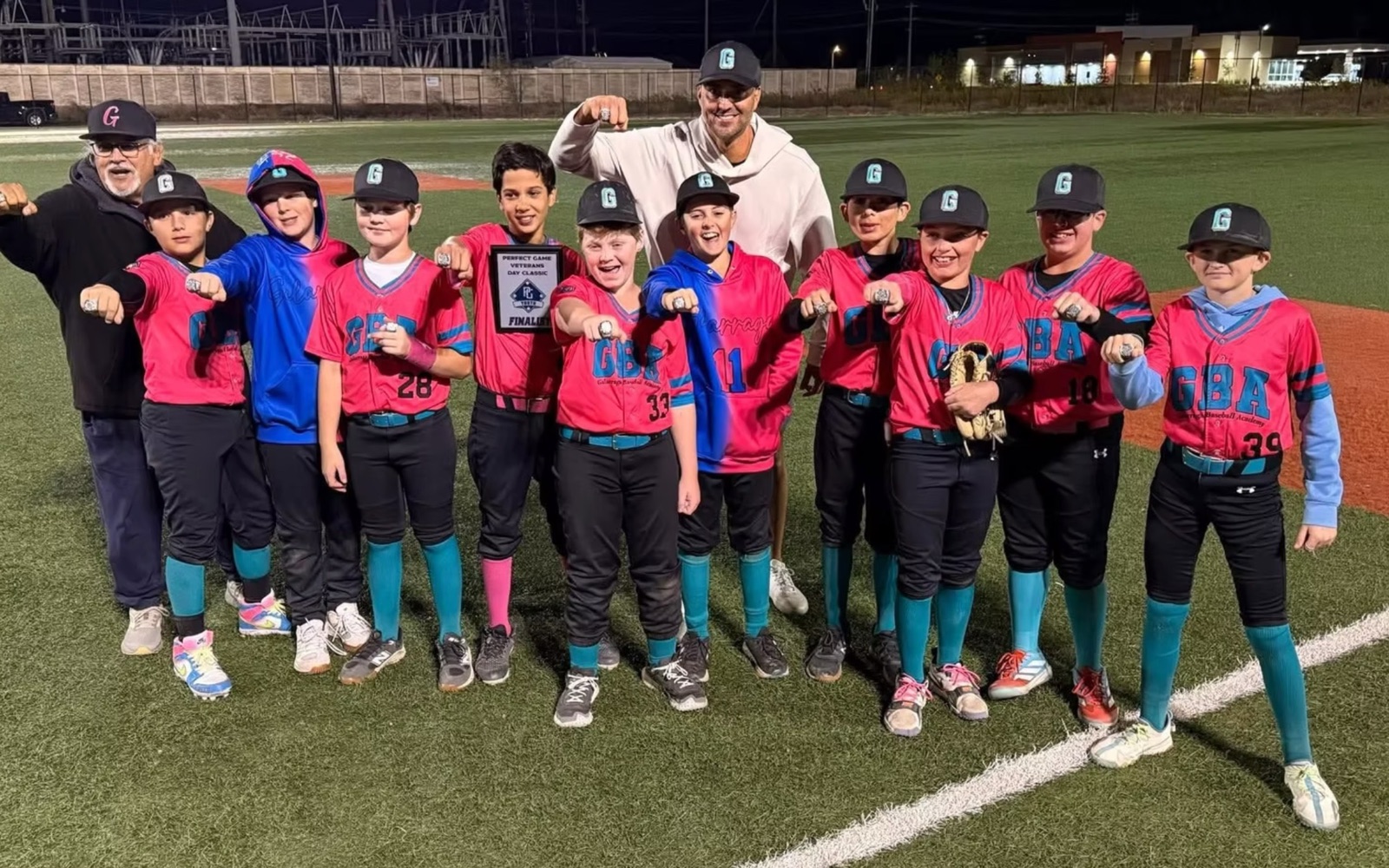 Galarraga Tigres players in pink GBA uniforms showing their tournament rings, with Armando and a coach